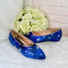 Load image into Gallery viewer, A pair of blue star-patterned shoes with white stars sits on a white surface, accompanied by a bouquet of white flowers.