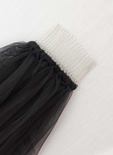 Load image into Gallery viewer, A black, sheer veil with a silver comb resting on it.