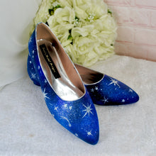 Load image into Gallery viewer, A pair of blue shoes with white star patterns on them, placed on a white surface next to a bouquet of white flowers.