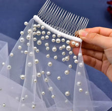 Load image into Gallery viewer, A hand is holding a white veil adorned with numerous small white pearls.