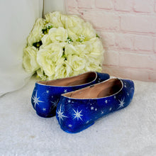 Load image into Gallery viewer, A pair of blue shoes with white star patterns sits on a white surface, with a bouquet of white roses in the background.