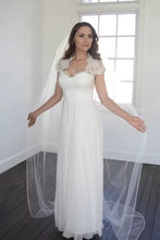 Load image into Gallery viewer, A woman in a white wedding dress stands in a room with a window, her arms outstretched.