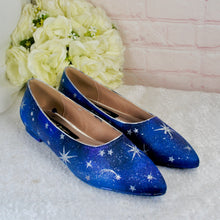 Load image into Gallery viewer, A pair of blue shoes with white star patterns is displayed on a white surface, with a bouquet of white roses in the background.
