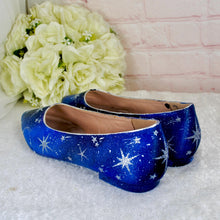 Load image into Gallery viewer, A pair of blue shoes with white star patterns is displayed on a white surface, with a bouquet of white roses in the background.
