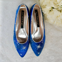 Load image into Gallery viewer, A pair of blue high-heeled shoes with white star patterns, placed on a white surface next to a bouquet of white flowers.
