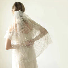 Load image into Gallery viewer, A woman wearing a white wedding dress with a sheer veil stands against a plain white background.
