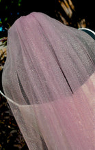 Load image into Gallery viewer, A close-up view of a delicate, pink, sheer veil with a sparkly texture, hanging from a frame.
