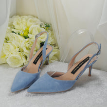 Load image into Gallery viewer, A pair of blue high-heeled shoes with a floral pattern, placed on a white surface next to a bouquet of white roses.
